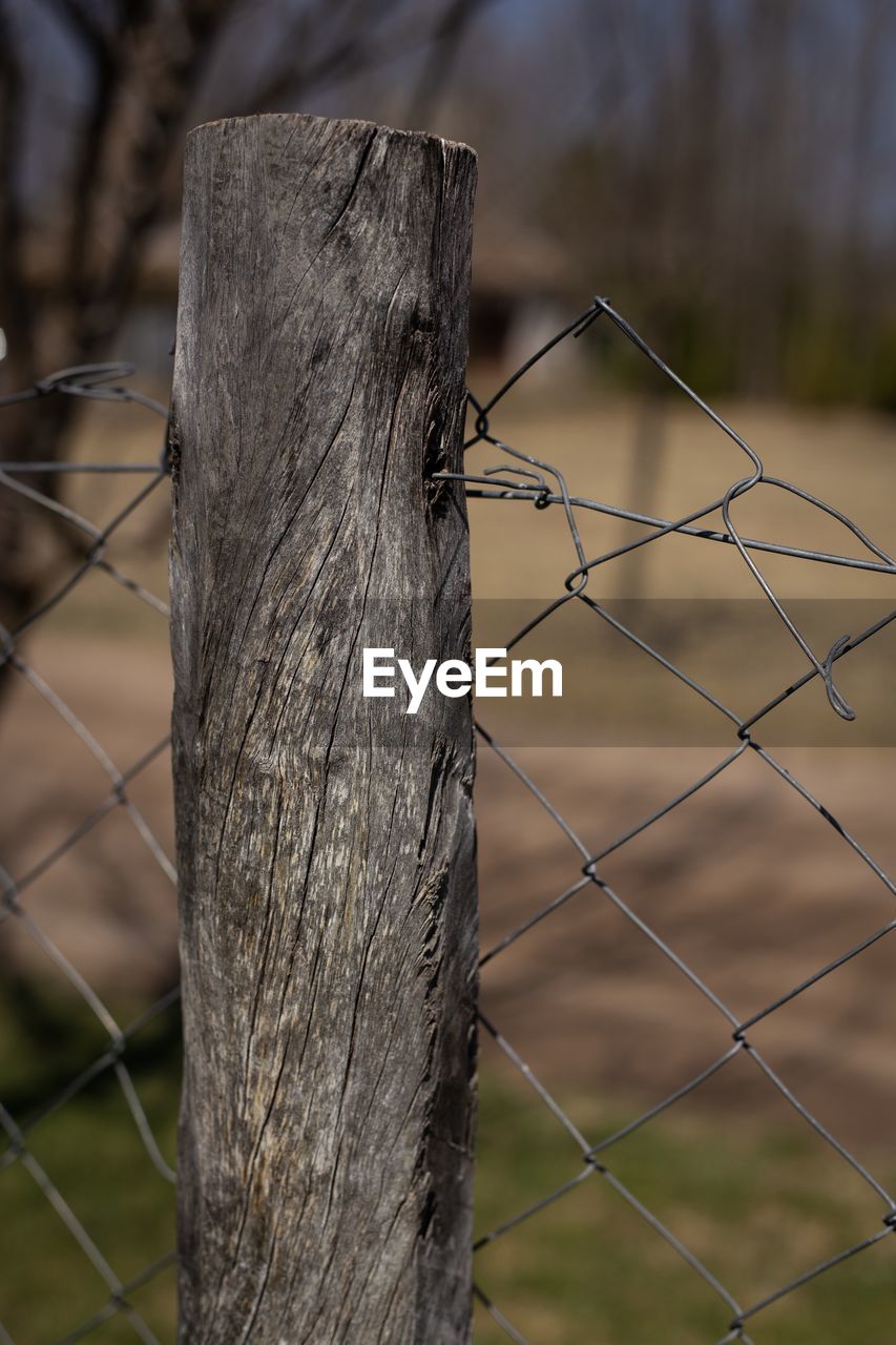 CLOSE-UP OF BARBED WIRE FENCE ON WOODEN POST