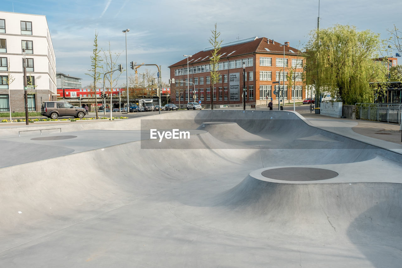 Skateboardpark  and road by buildings in city against sky