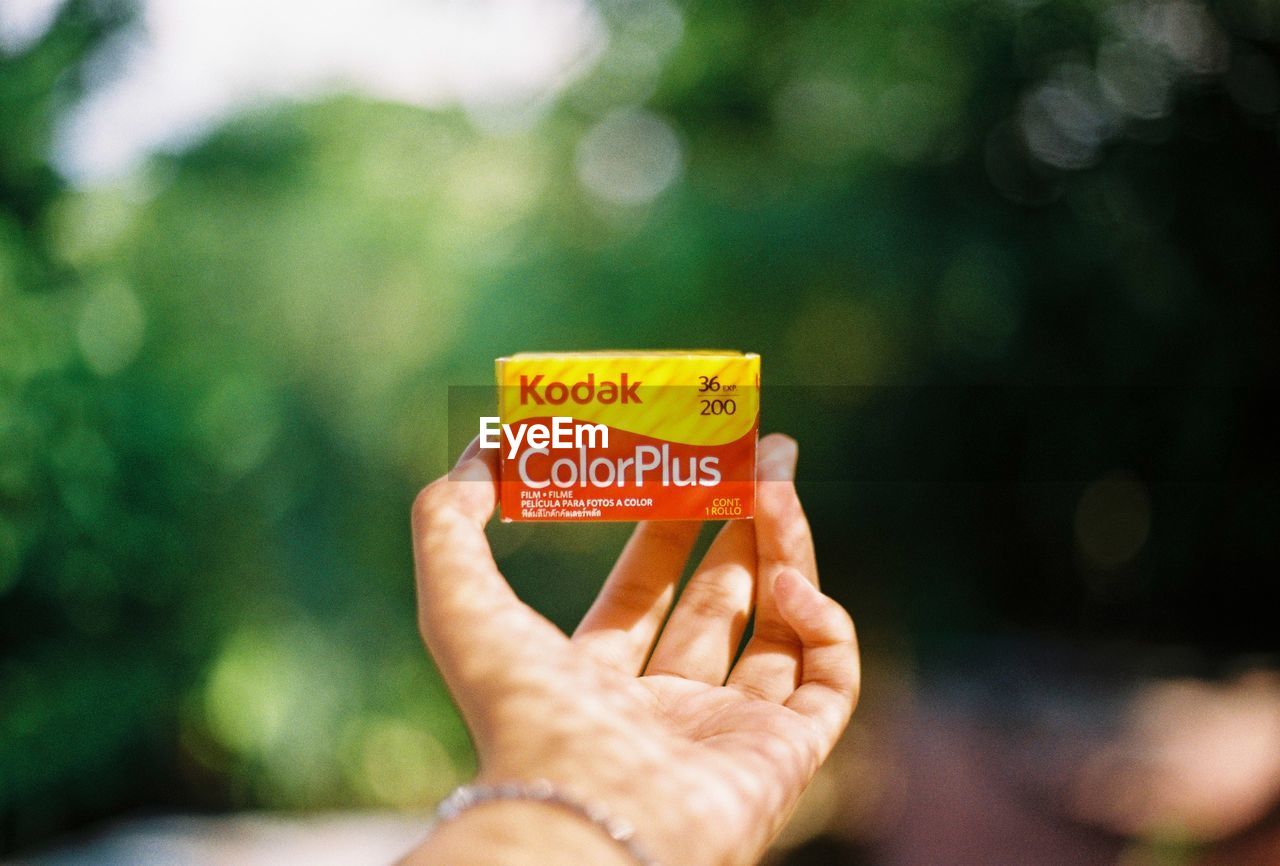 CLOSE-UP OF HAND HOLDING YELLOW TEXT ON FINGER