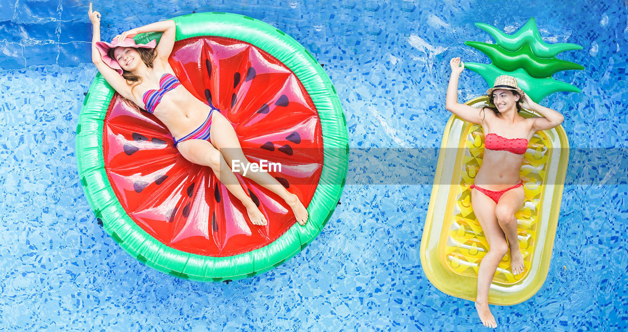 High angle view of female friends relaxing on inflatable rings in swimming pool