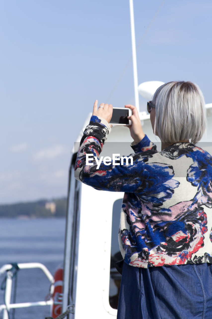 Rear view of woman standing on boat against sky