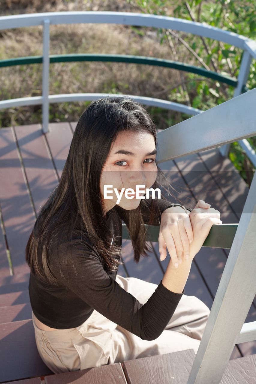 Portrait of woman sitting on railing