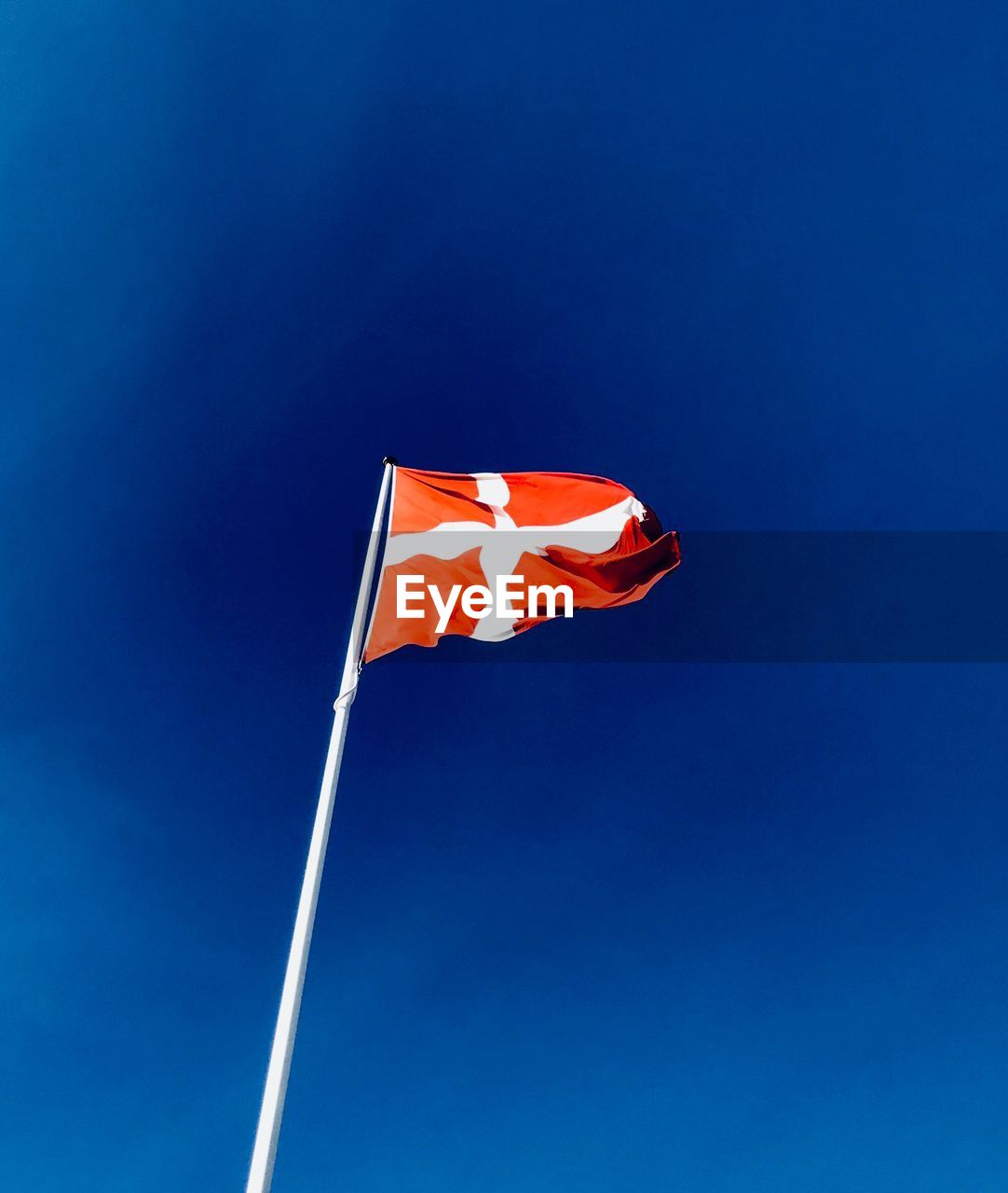 Low angle view of danish flag against blue sky