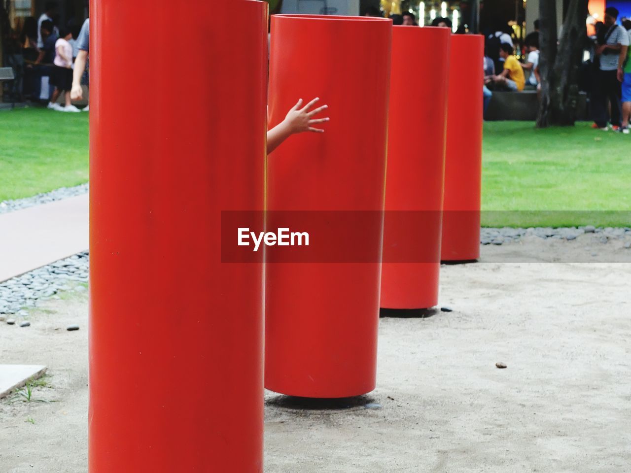 Cropped image of child hand touching red playing equipment in park