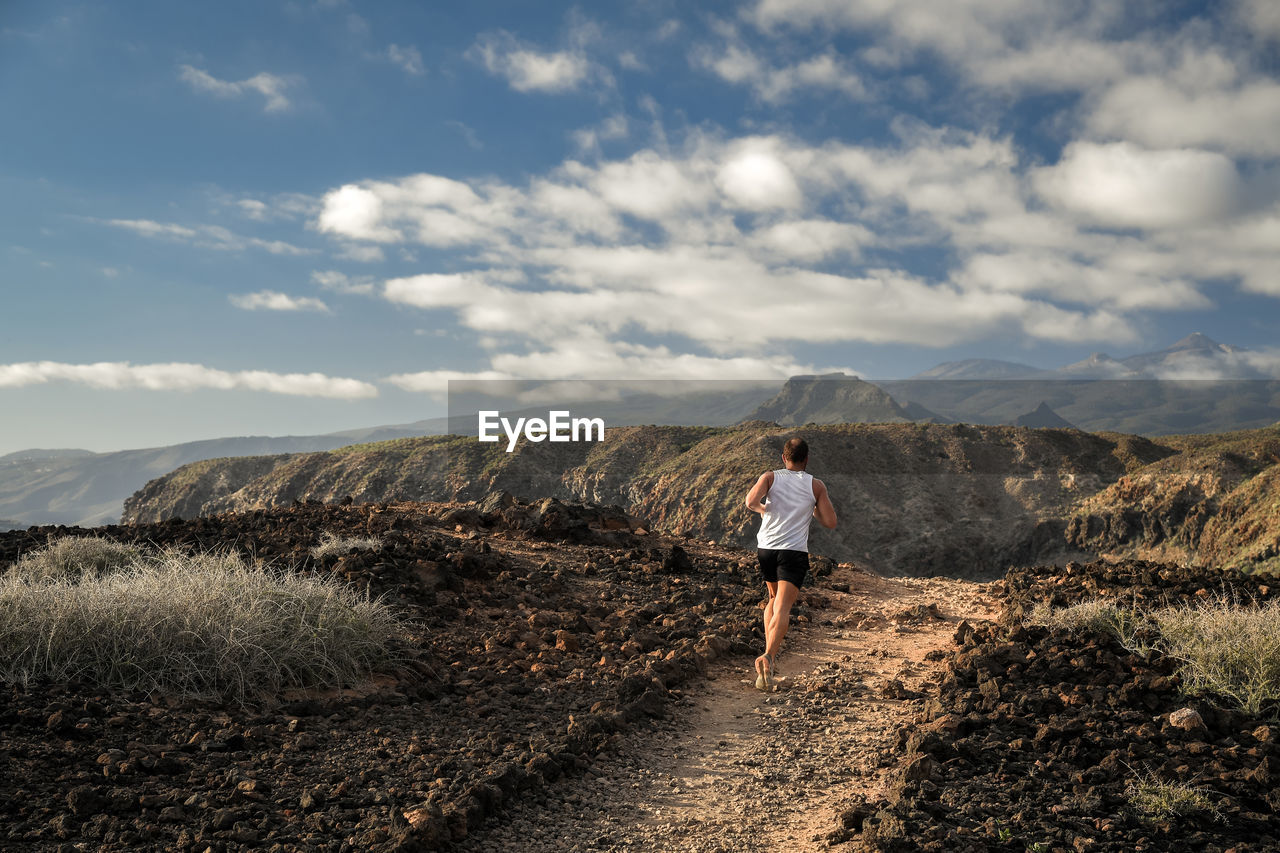 Rear view of man running on mountain against sky