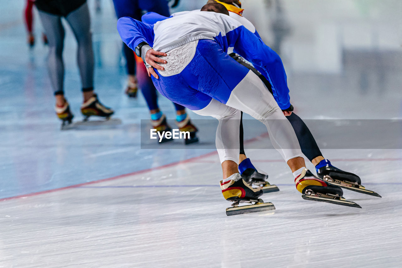 Back men speed skaters running in ice ring