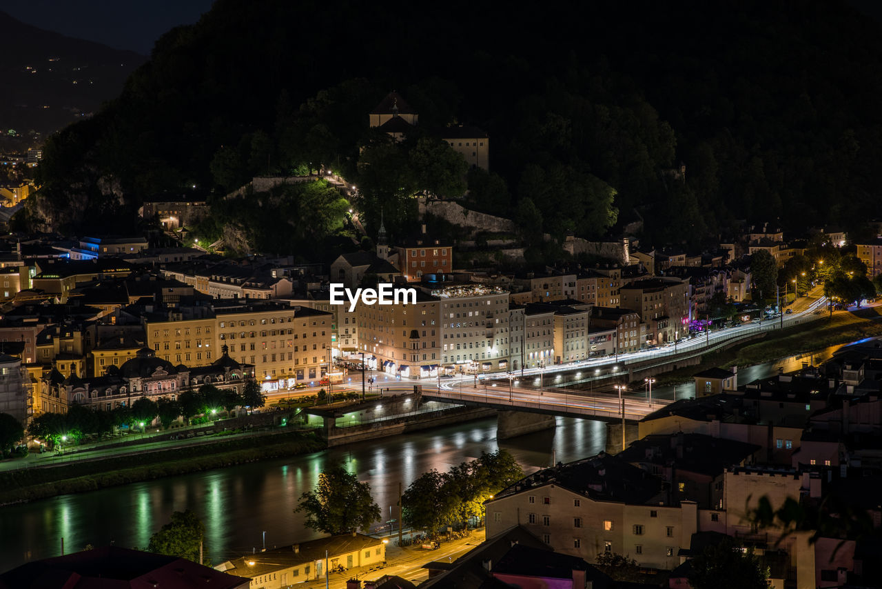 HIGH ANGLE VIEW OF ILLUMINATED CITY BUILDINGS AT NIGHT