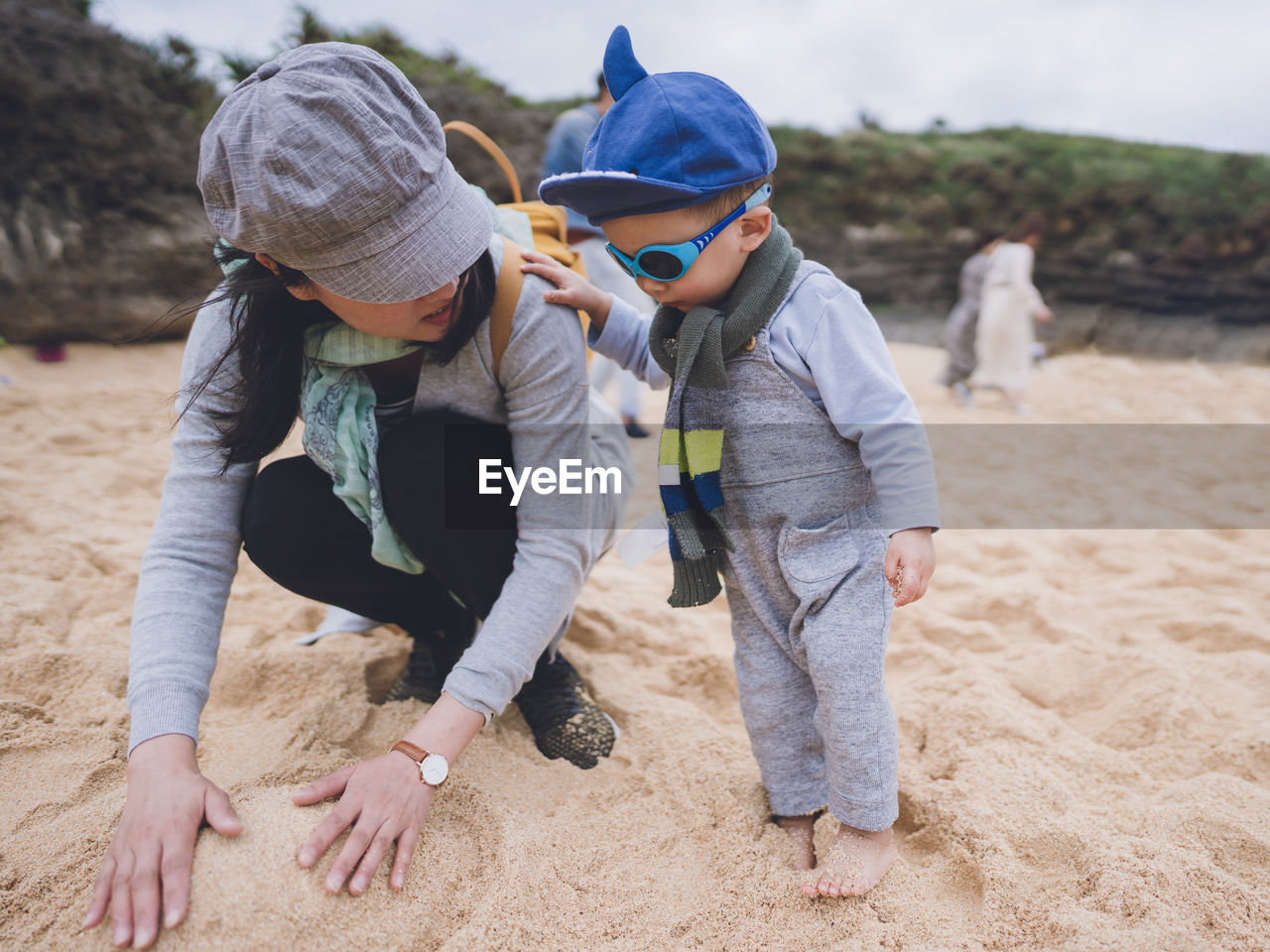 Mother and her baby boy playing sand on a beach