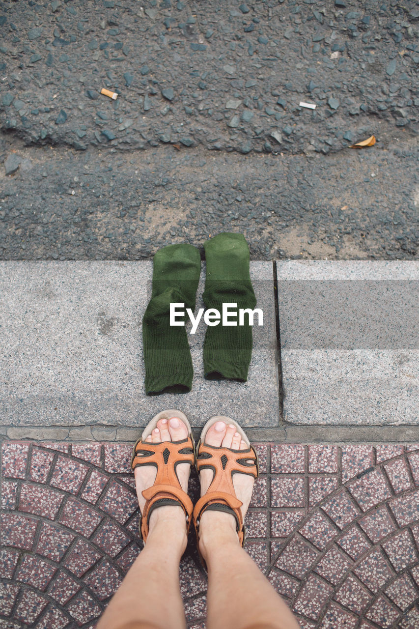 Low section of woman by socks on sidewalk