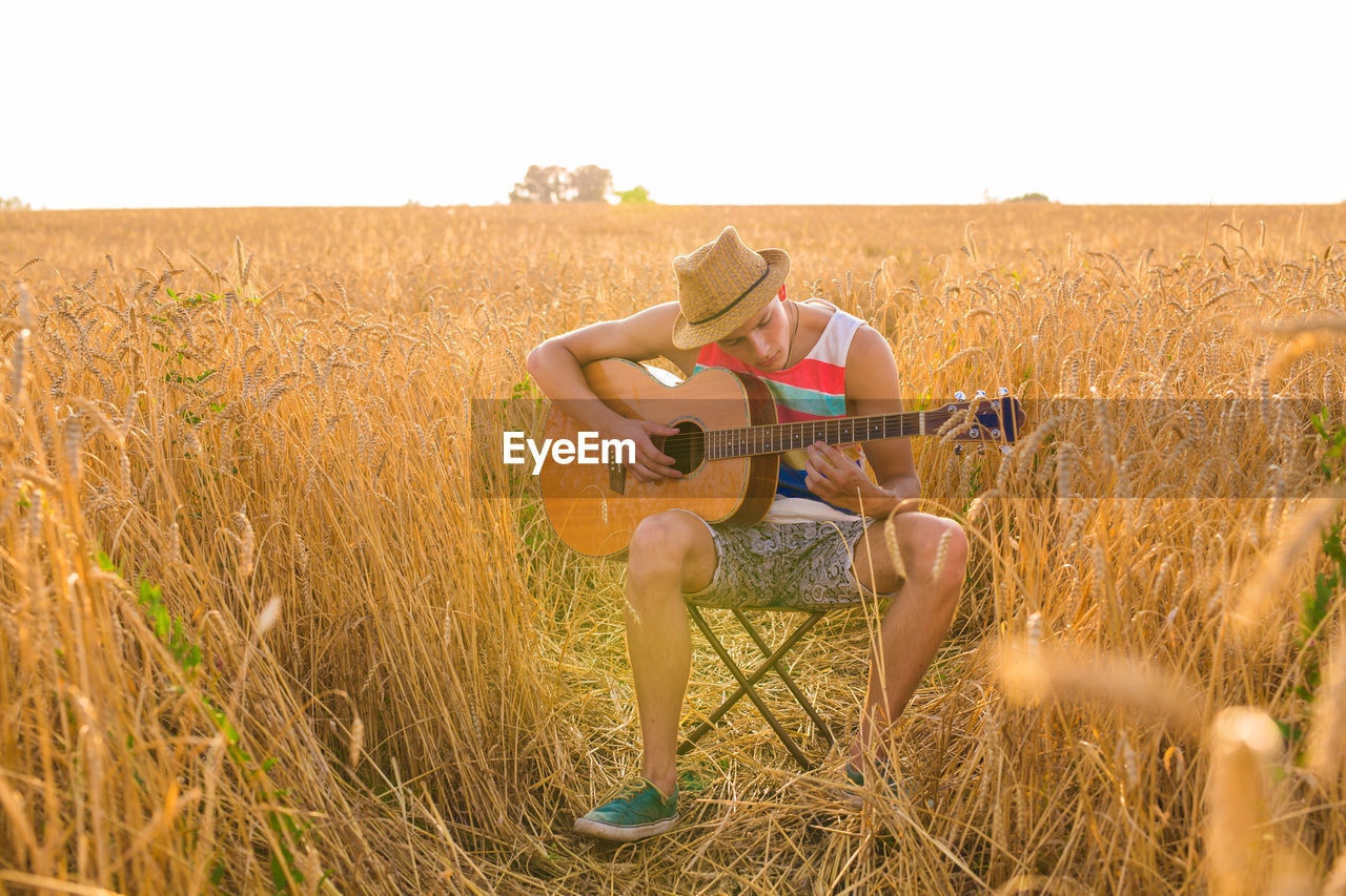 MAN PLAYING GUITAR IN FIELD