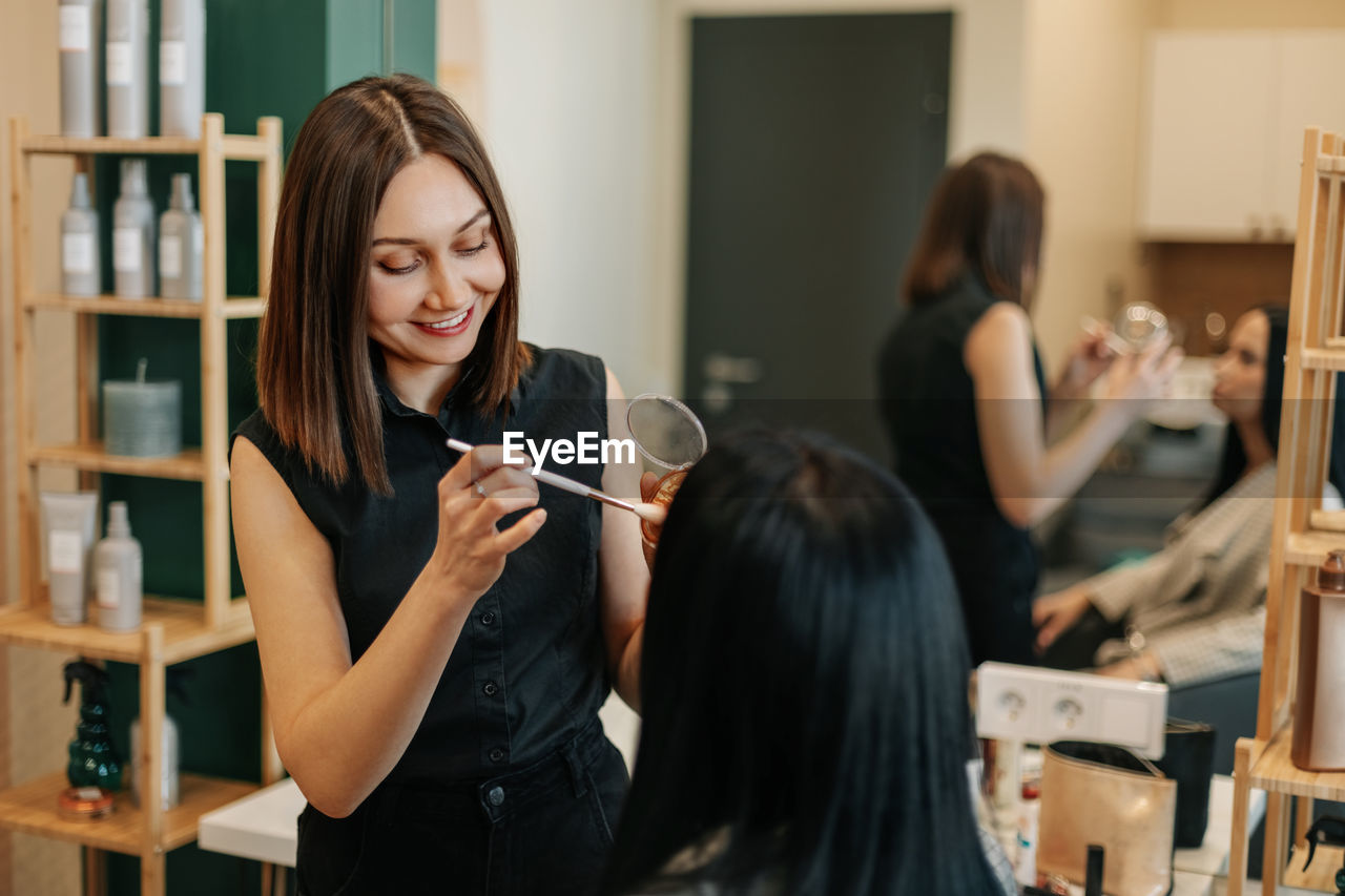 The makeup artist works in her salon, applies professional makeup. beauty industry, make-up