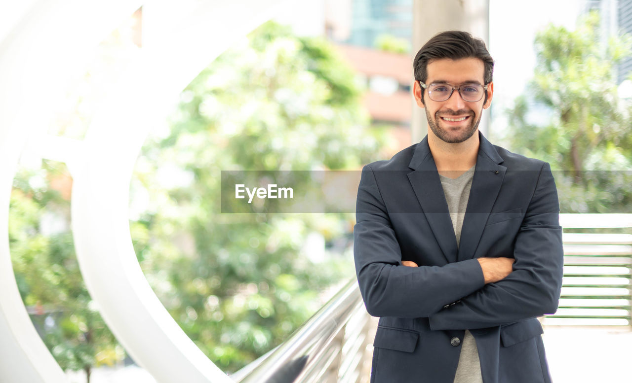 The portrait of a happy young handsome caucasian businessman with eyeglasses and suits.