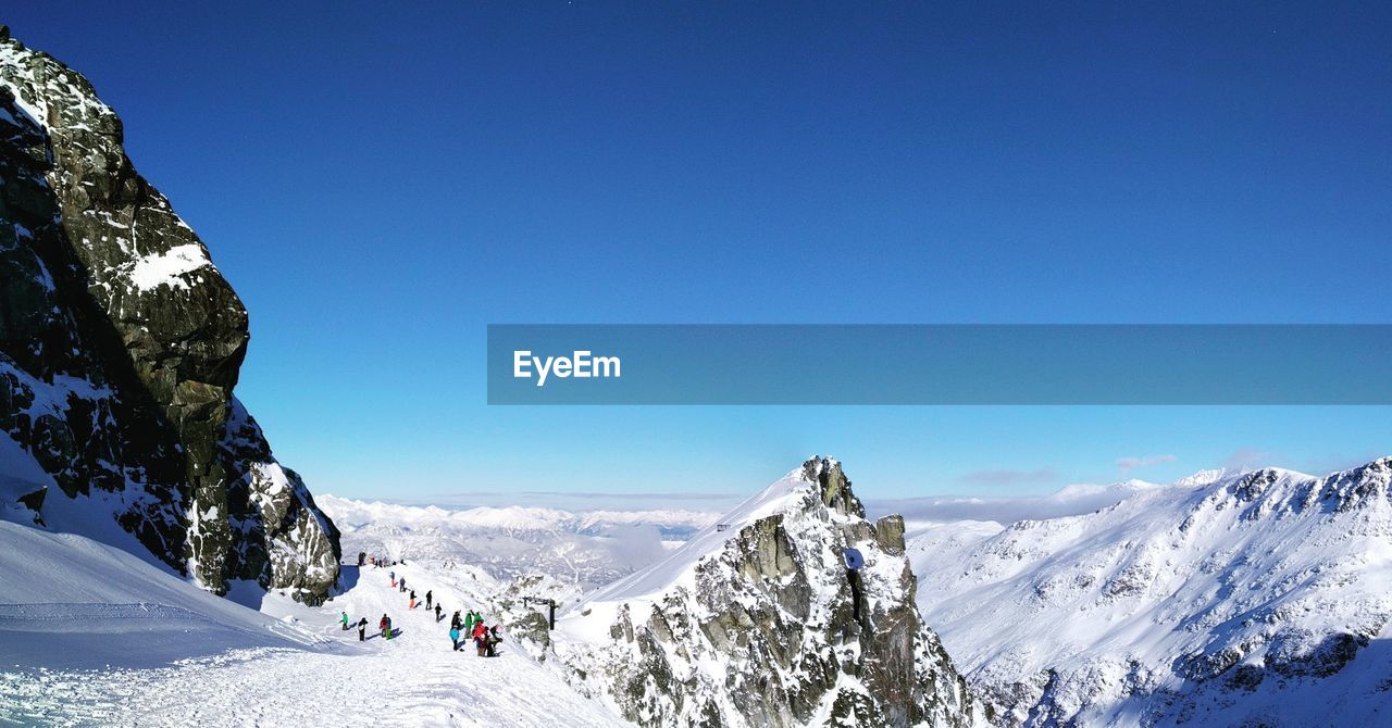 PANORAMIC VIEW OF SNOWCAPPED MOUNTAIN AGAINST CLEAR BLUE SKY