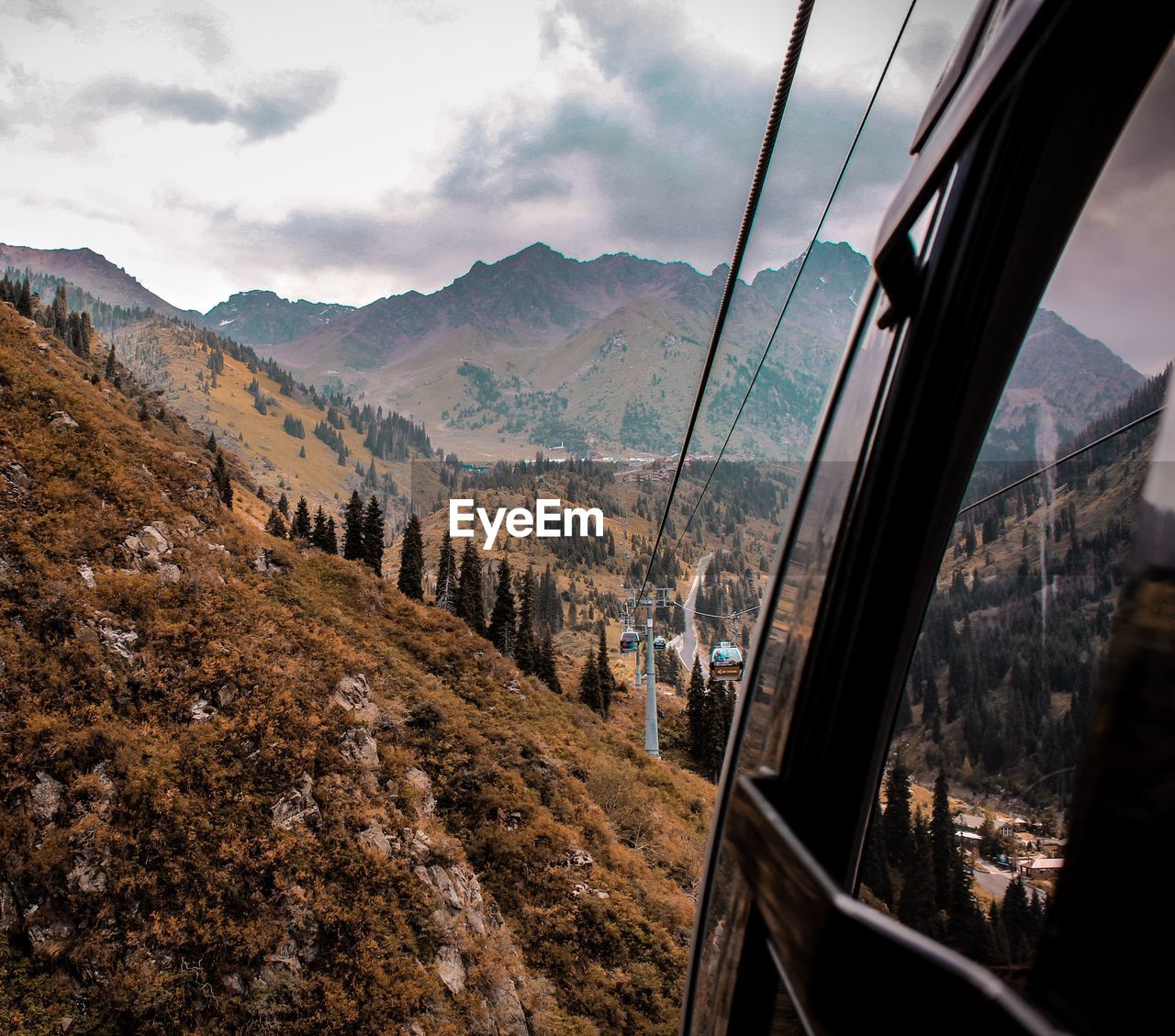 Overhead cable cars over mountains against cloudy sky