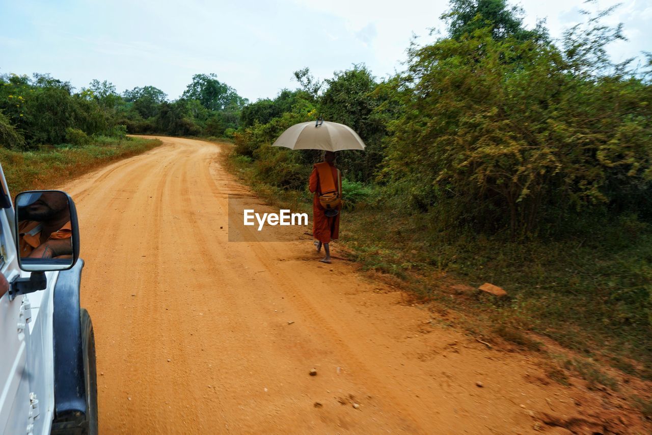 REAR VIEW OF MAN CYCLING ON ROAD