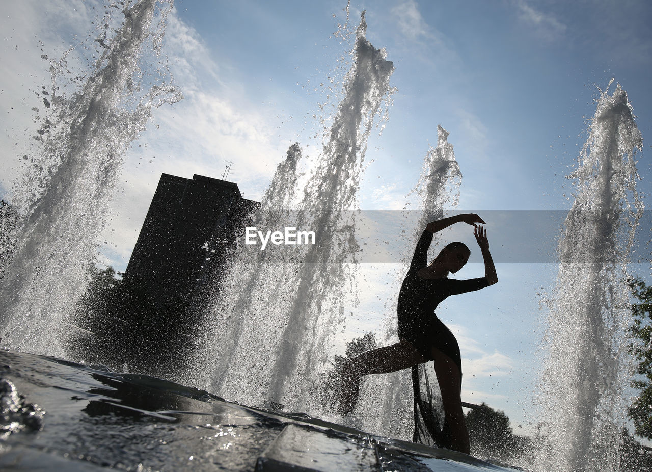 LOW ANGLE VIEW OF MAN SPLASHING WATER