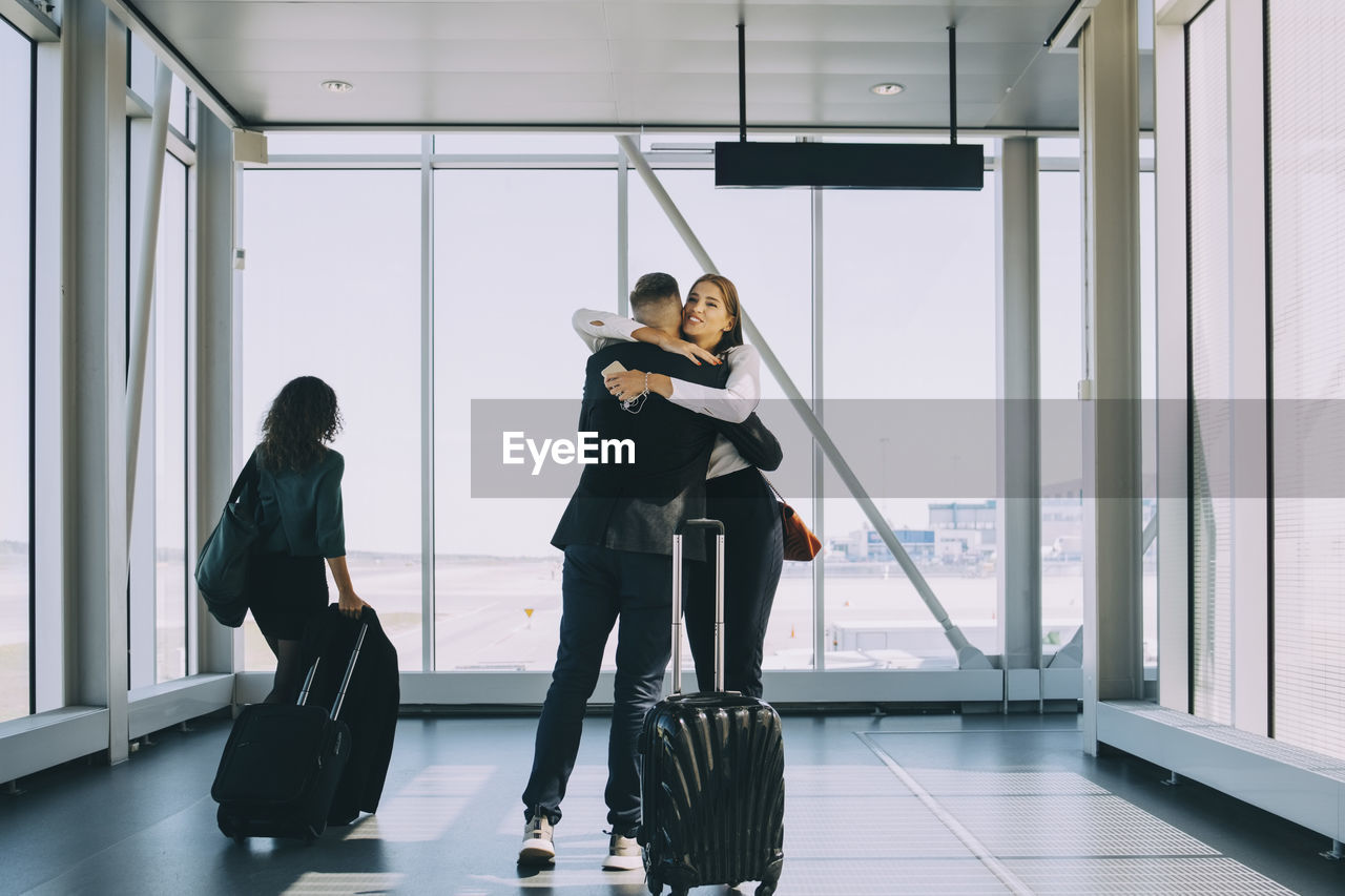 Businesswoman walking by colleagues greeting in corridor at airport