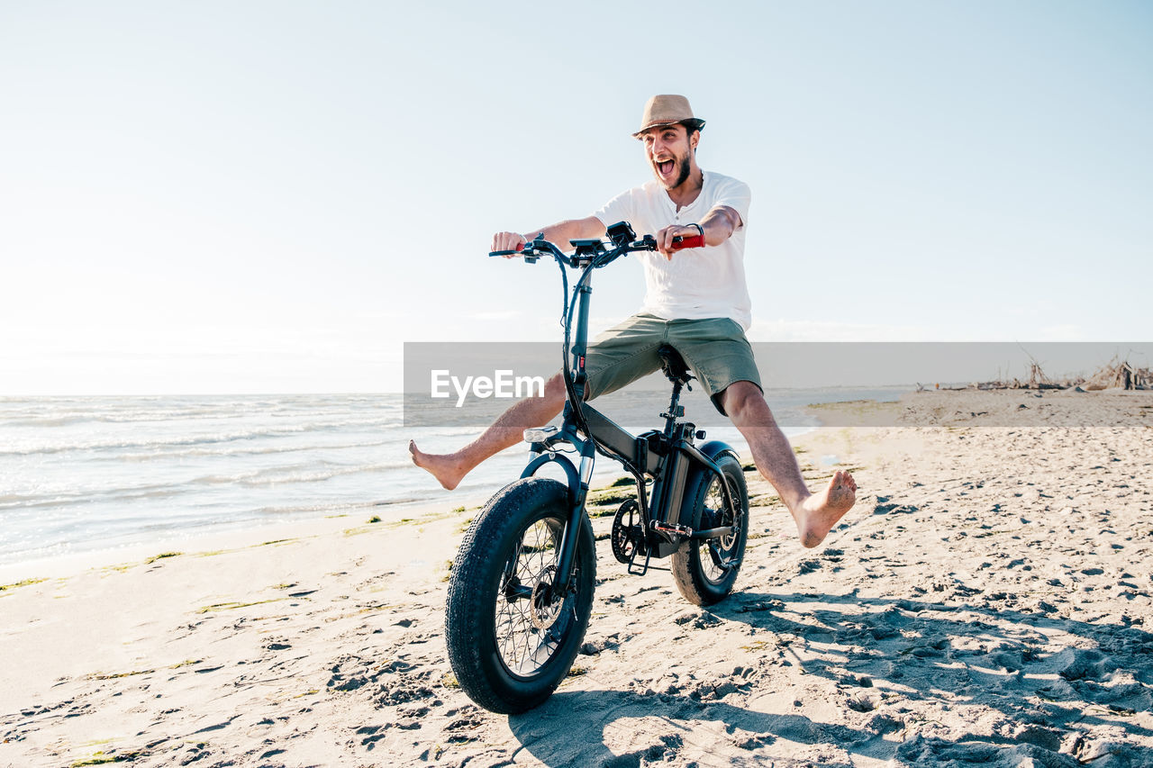 rear view of man riding bicycle on beach