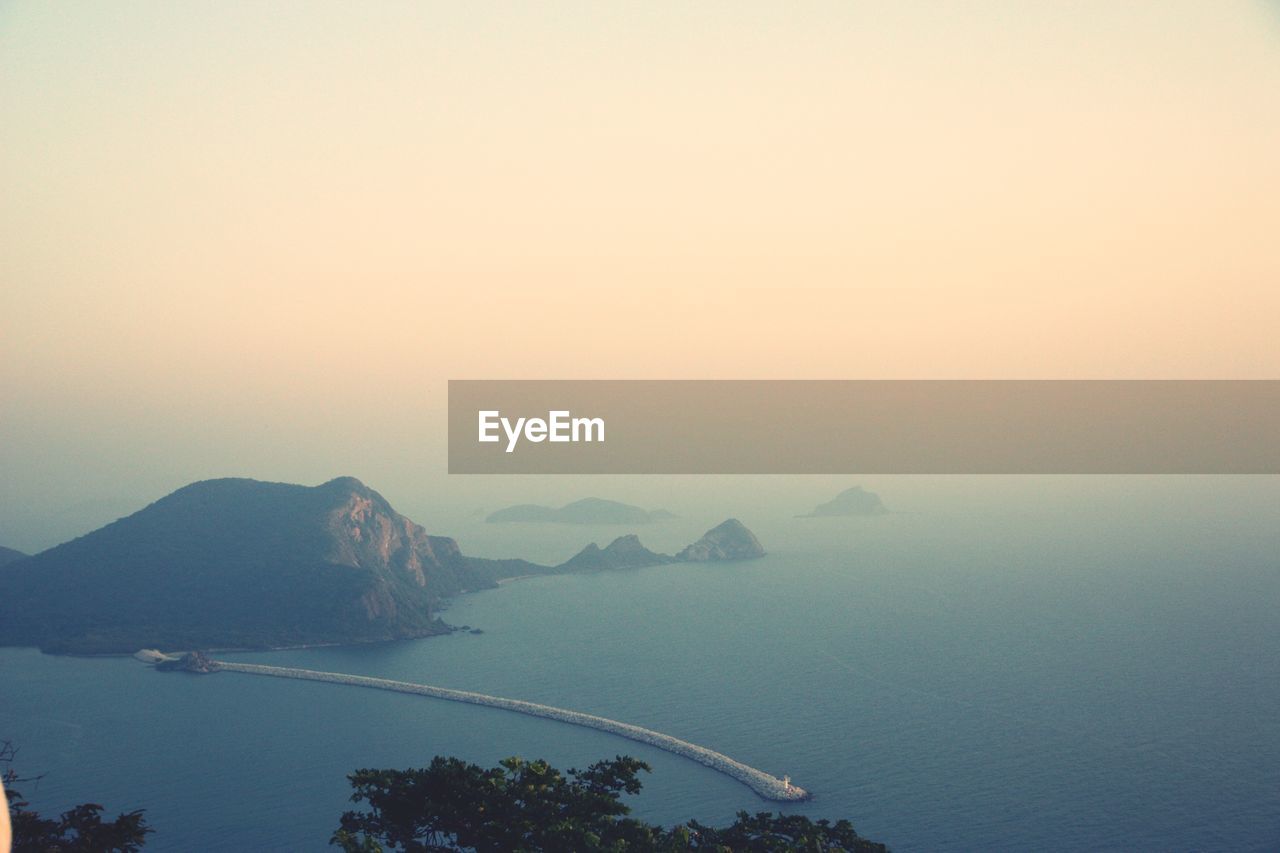 Scenic view of sea and mountains against clear sky