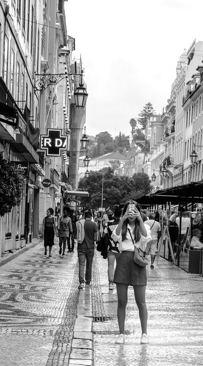 architecture, road, street, city, building exterior, built structure, black and white, group of people, infrastructure, walking, monochrome photography, women, monochrome, adult, city life, men, snapshot, large group of people, building, lifestyles, crowd, day, footwear, sky, city street, nature, town, person, travel, travel destinations, full length, clothing, cityscape, outdoors, tourism, urban area, transportation, footpath, leisure activity, rear view