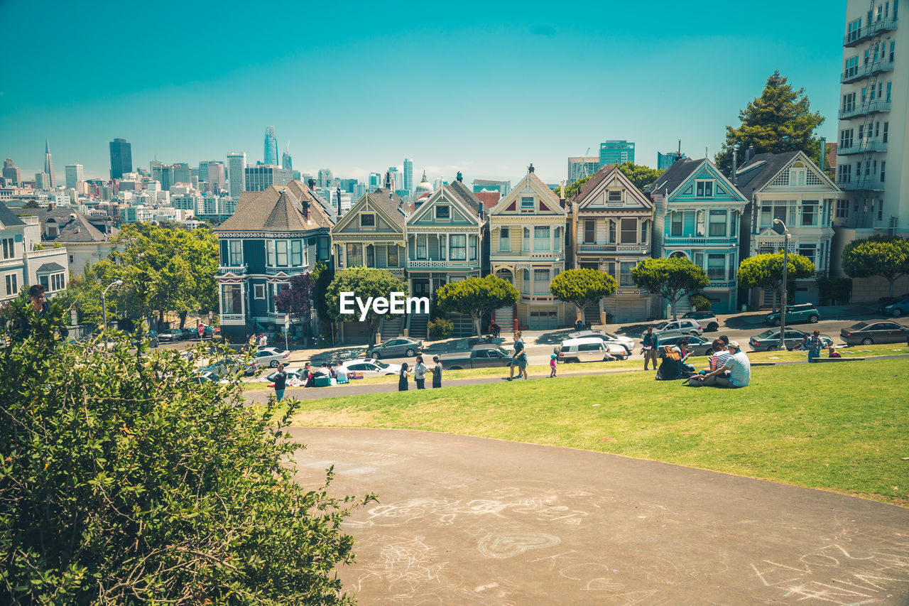 Houses by street and buildings against blue sky