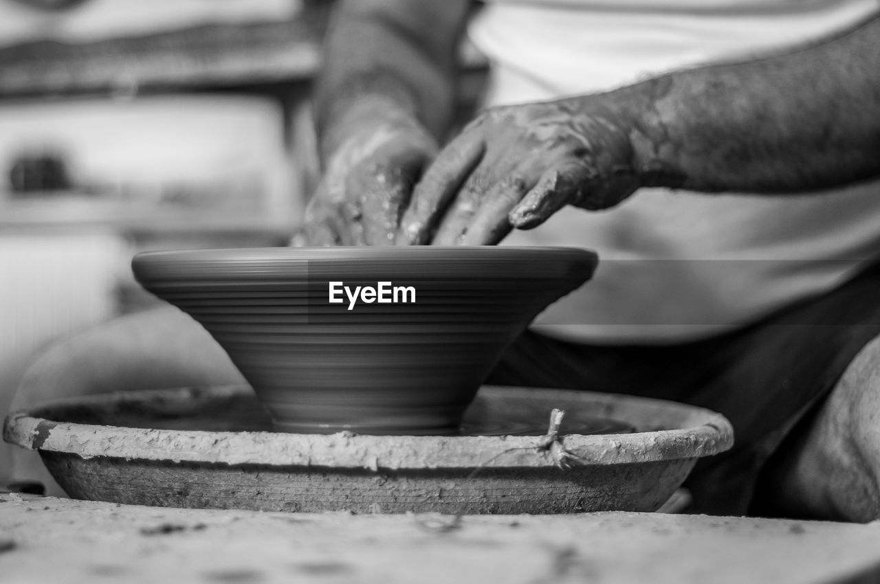 Cropped hands of potter making pot in pottery workshop