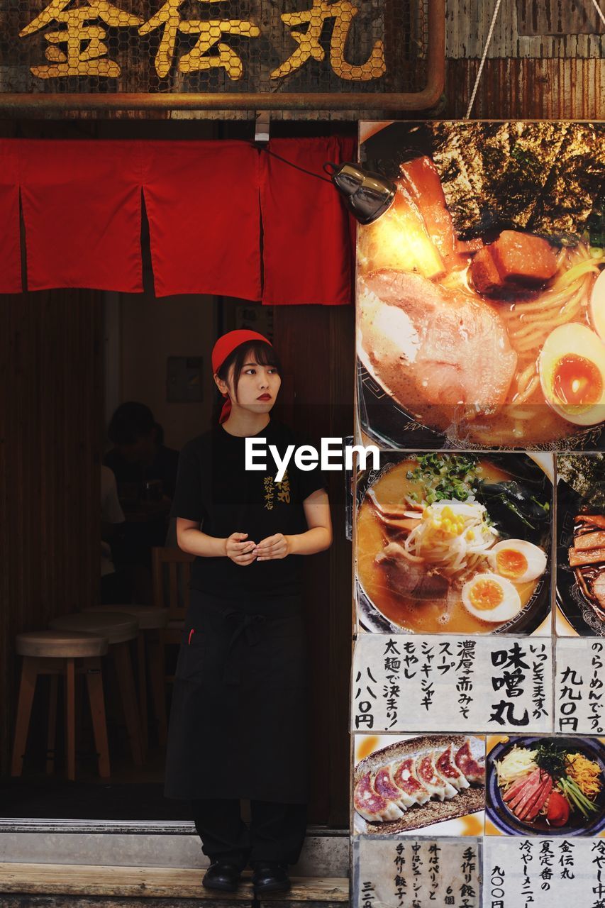 WOMAN HOLDING FOOD WHILE STANDING BY TABLE