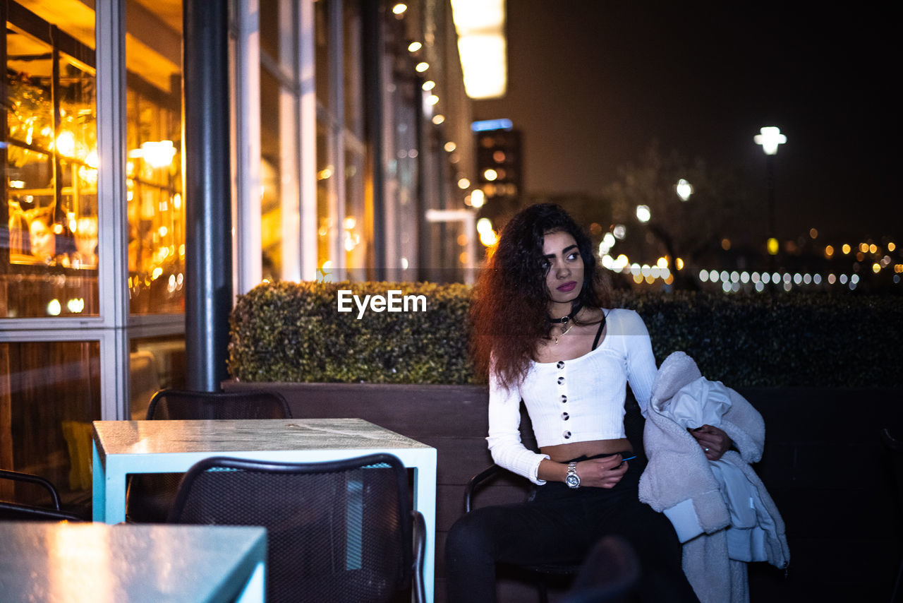 Woman sitting on chair at sidewalk cafe