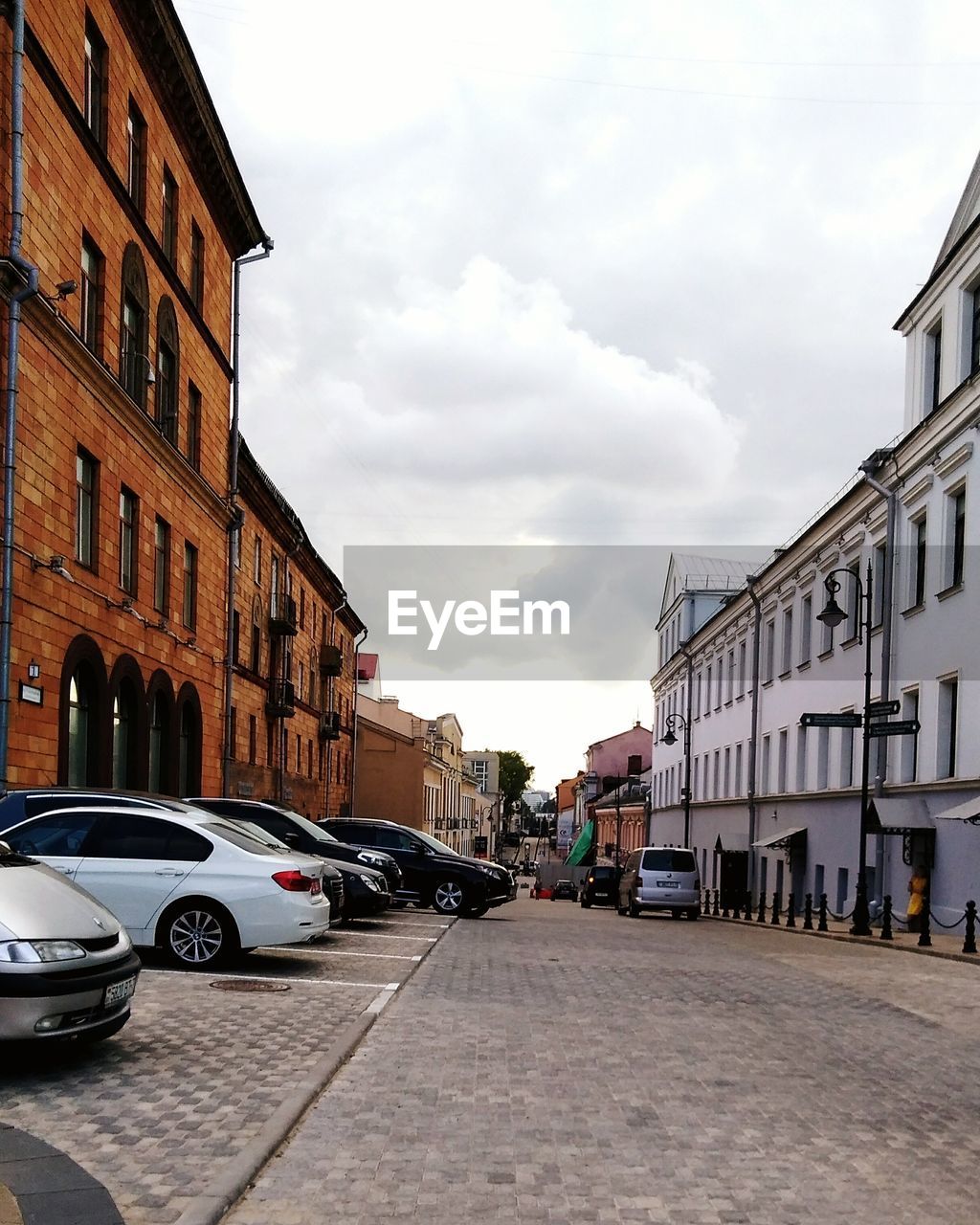 STREET AMIDST BUILDINGS IN CITY AGAINST SKY