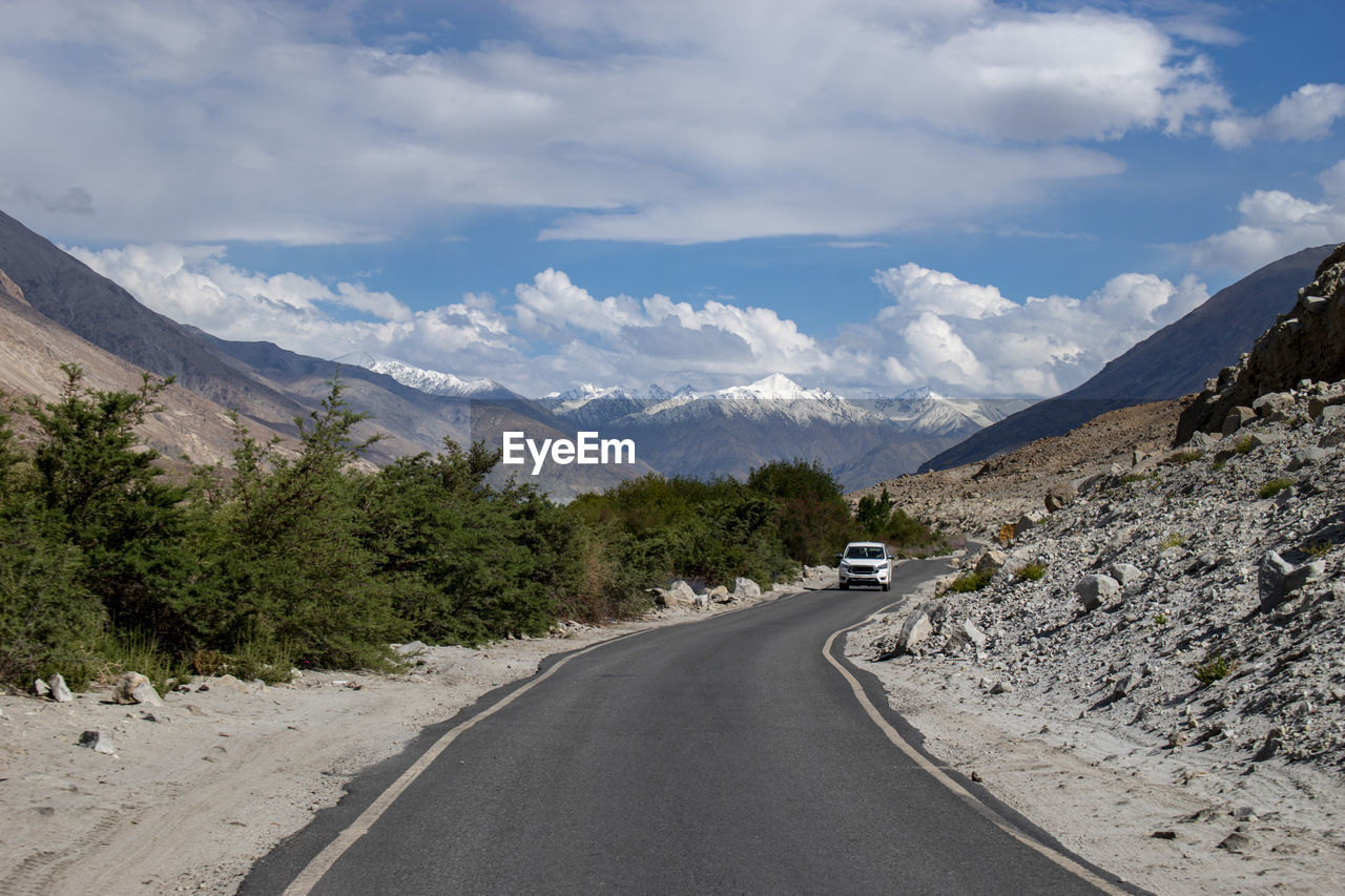 panoramic view of road by mountain against sky