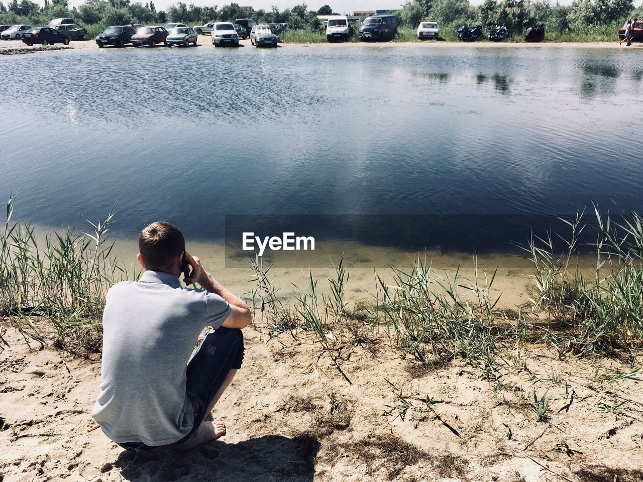 REAR VIEW OF WOMAN LOOKING AT LAKE