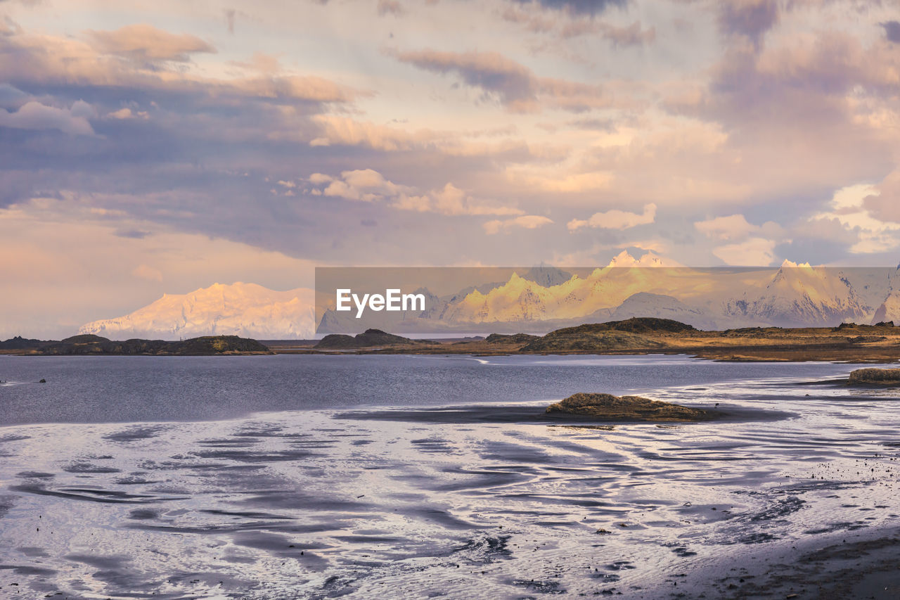 Scenic view of rocky mountains with snow in winter near stockness beach under cloudy sky in iceland