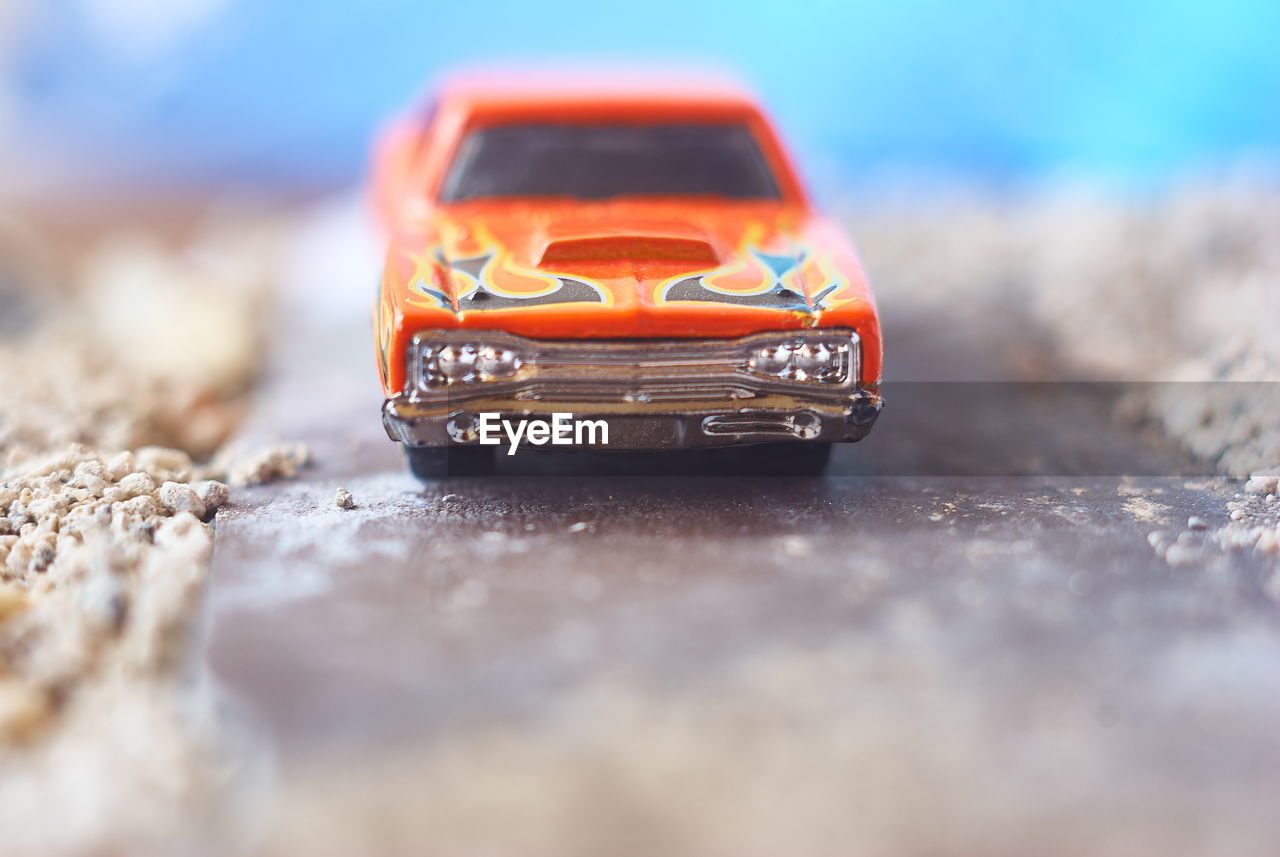 CLOSE-UP OF TOY CAR ON TABLE AT RAILROAD TRACK