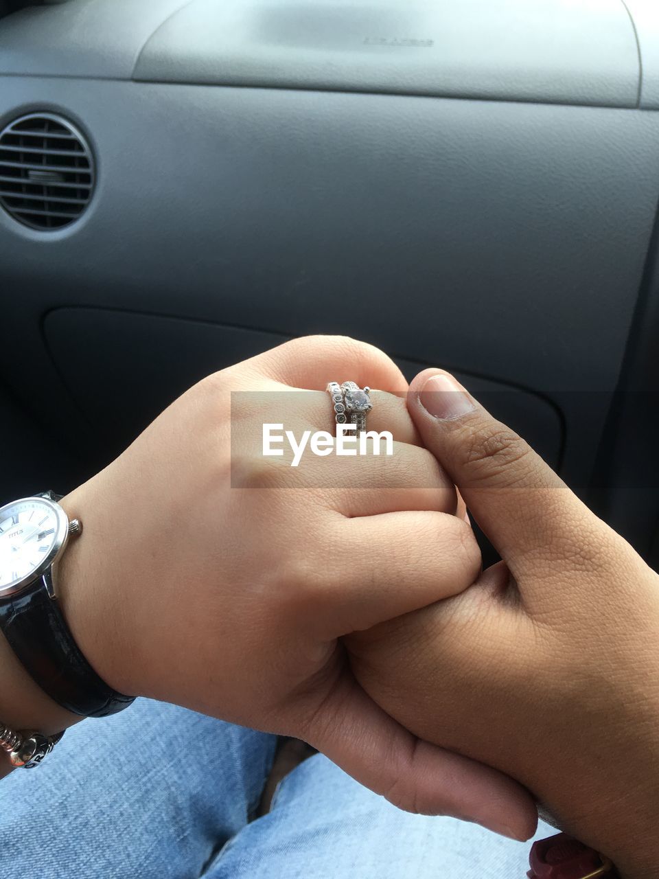 MIDSECTION OF COUPLE HOLDING HANDS WITH CAR