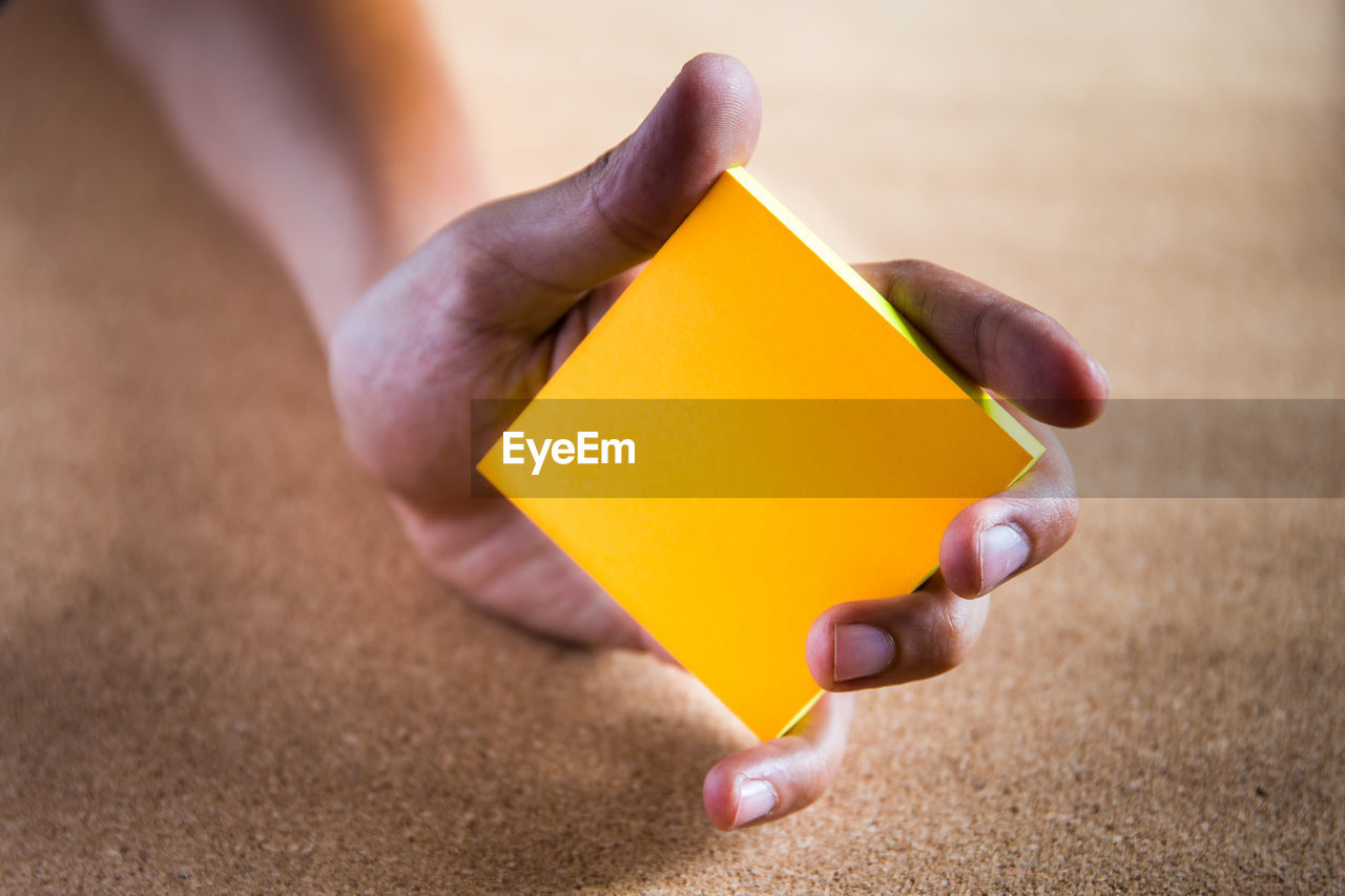 Close-up of person holding orange paper