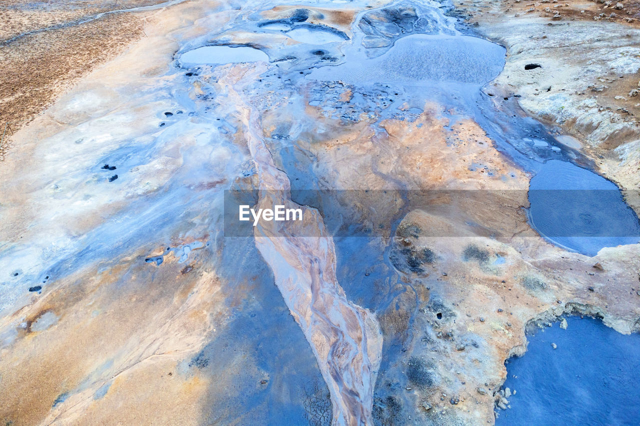 Aerial top view of blue mud bubbling in rough crater in hverir geothermal area in daytime in reykjahlid, iceland