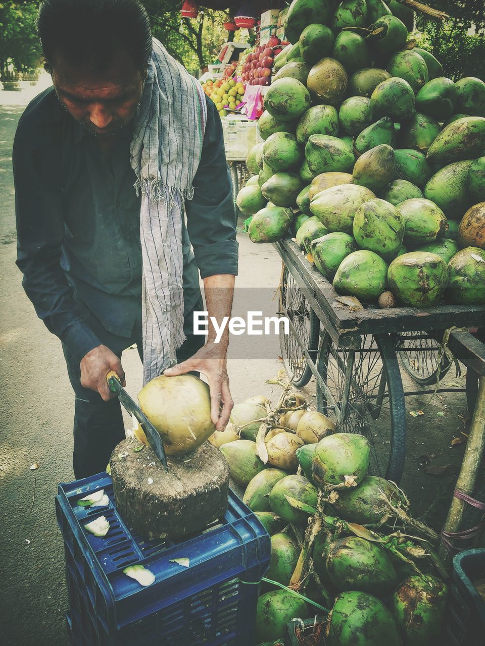 Vendor peeling coconuts at market stall