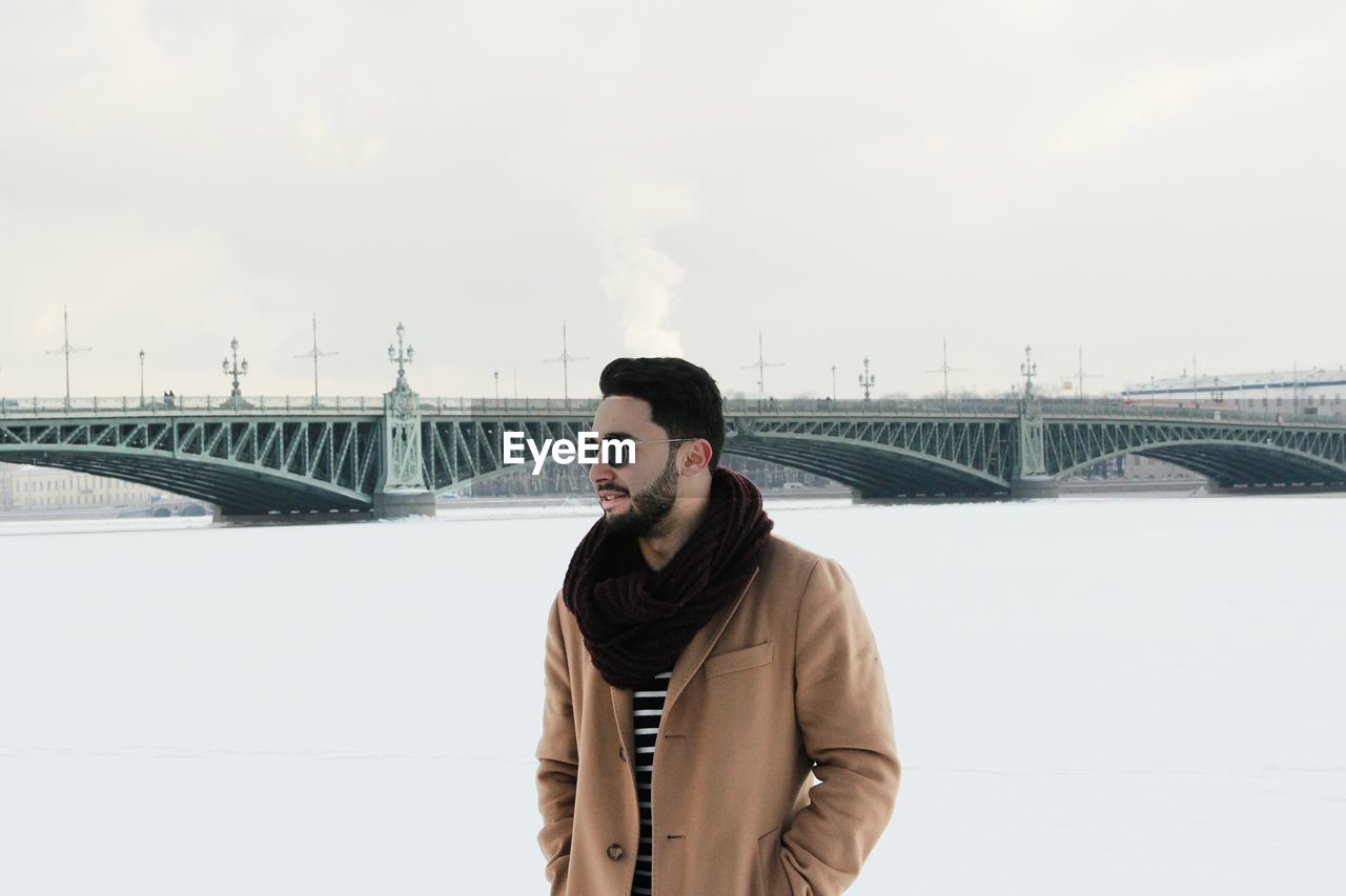 Portrait of young man in city against sky