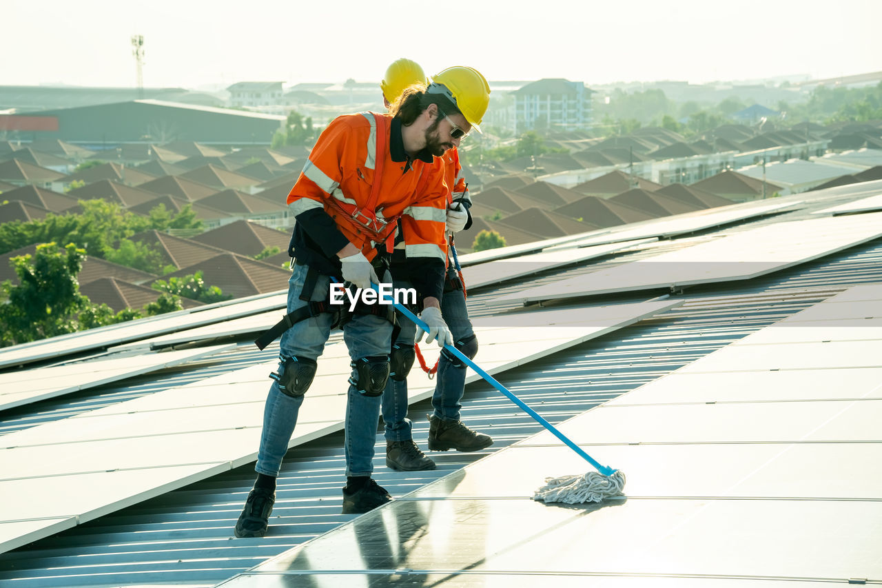 adult, full length, men, working, occupation, headwear, helmet, architecture, manual worker, cleanliness, clothing, nature, person, protection, sports, one person, cleaning, protective workwear, day, reflective clothing, built structure, industry, sky, roof, holding, outdoors