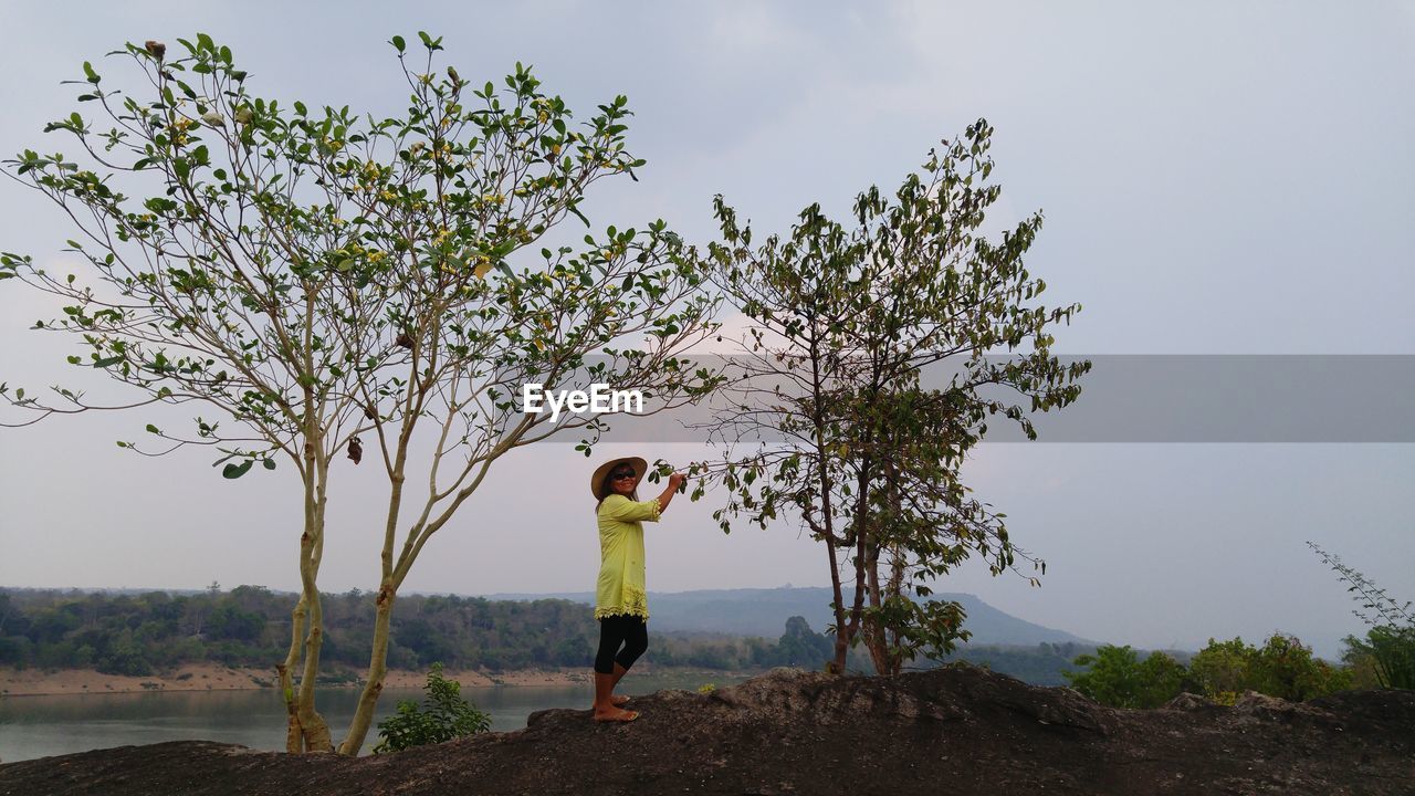 SILHOUETTE OF WOMAN STANDING ON TREE