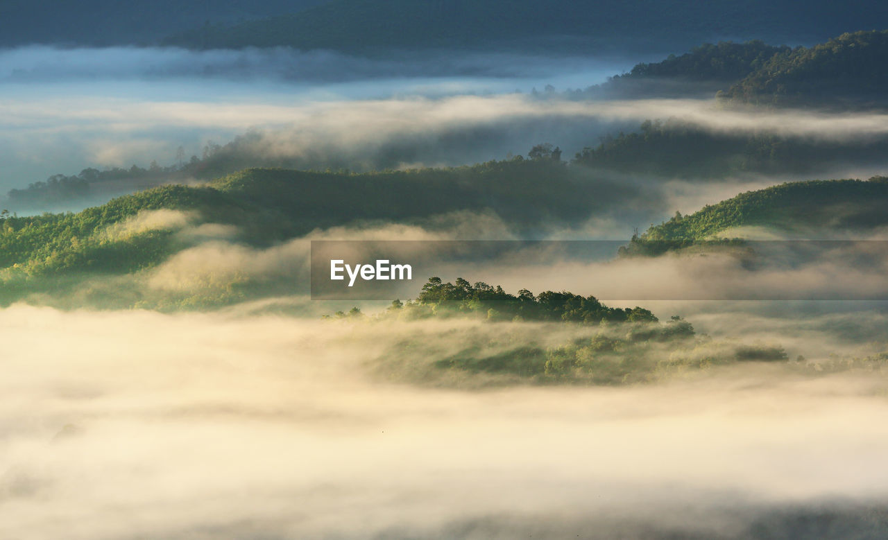 Scenic view of mountains against sky during sunset at foggy weather