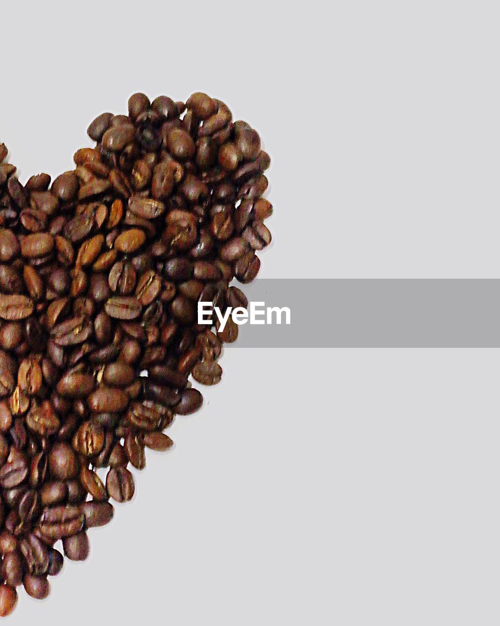 Heart shape made from coffee beans with area for copy space against white background 