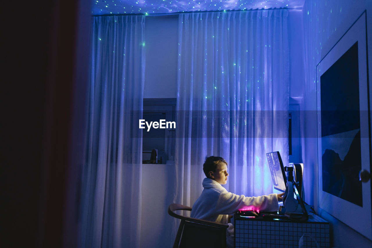 Boy at desk using computer at night