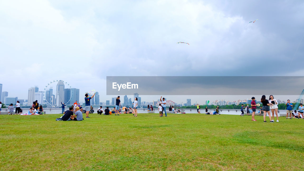 GROUP OF PEOPLE ON GRASS AGAINST SKY