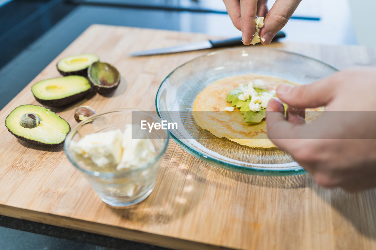 Man cooking in the kitchen in a denim shirt. an anonymous man is cooking pancakes with feta cheese and avocado