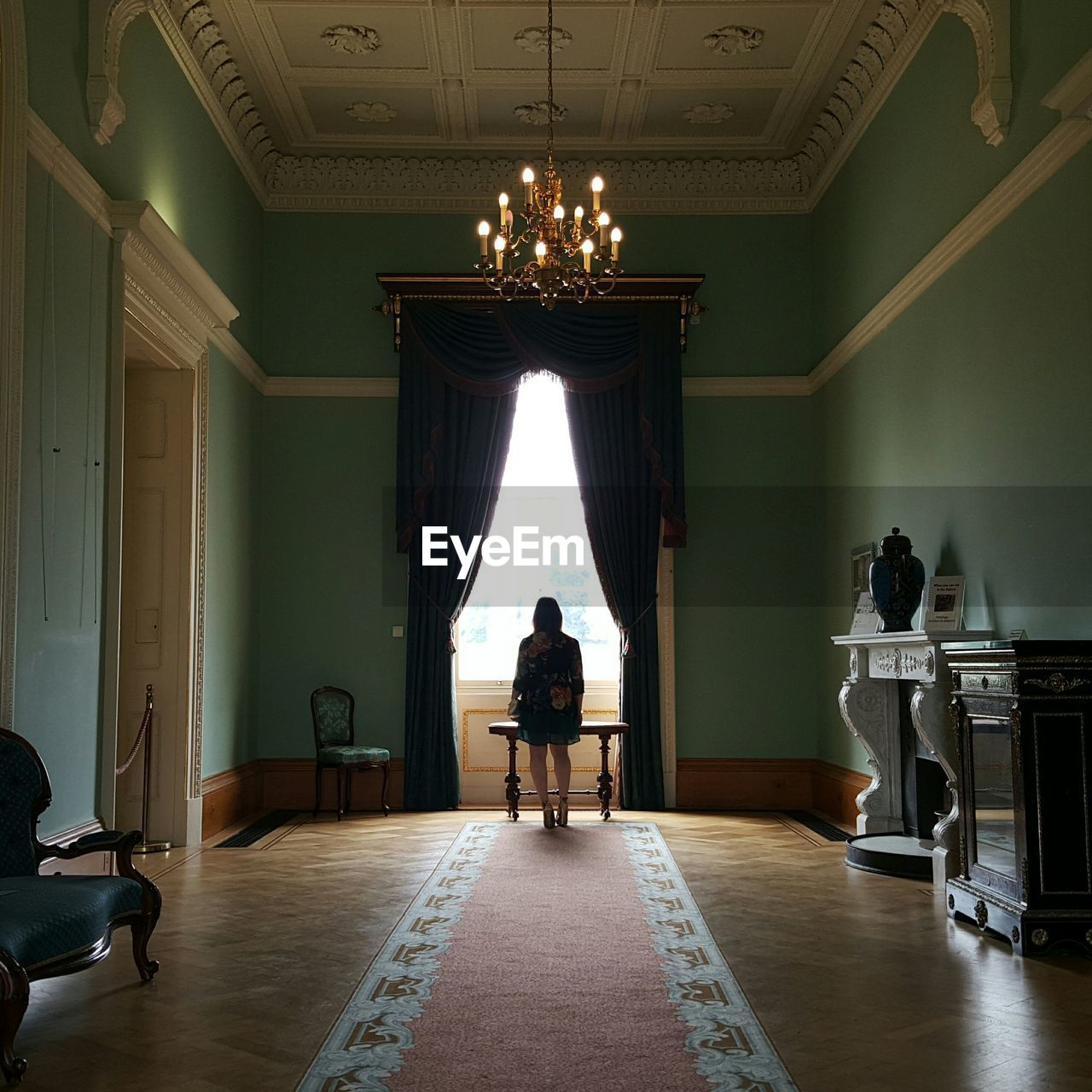 Rear view of woman standing by window in corridor