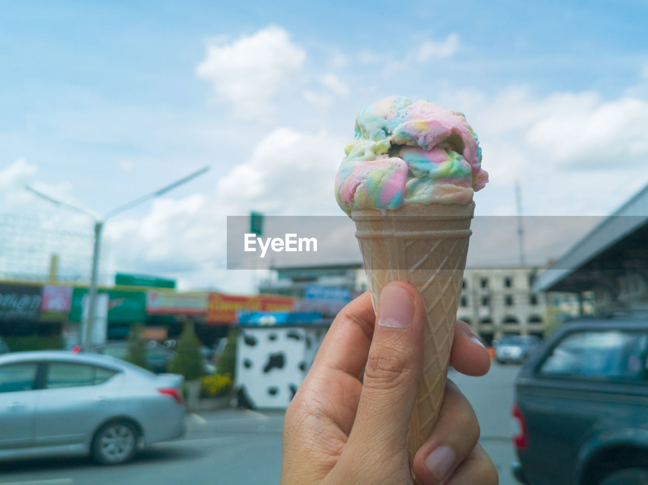 Hand holding ice cream cone on street