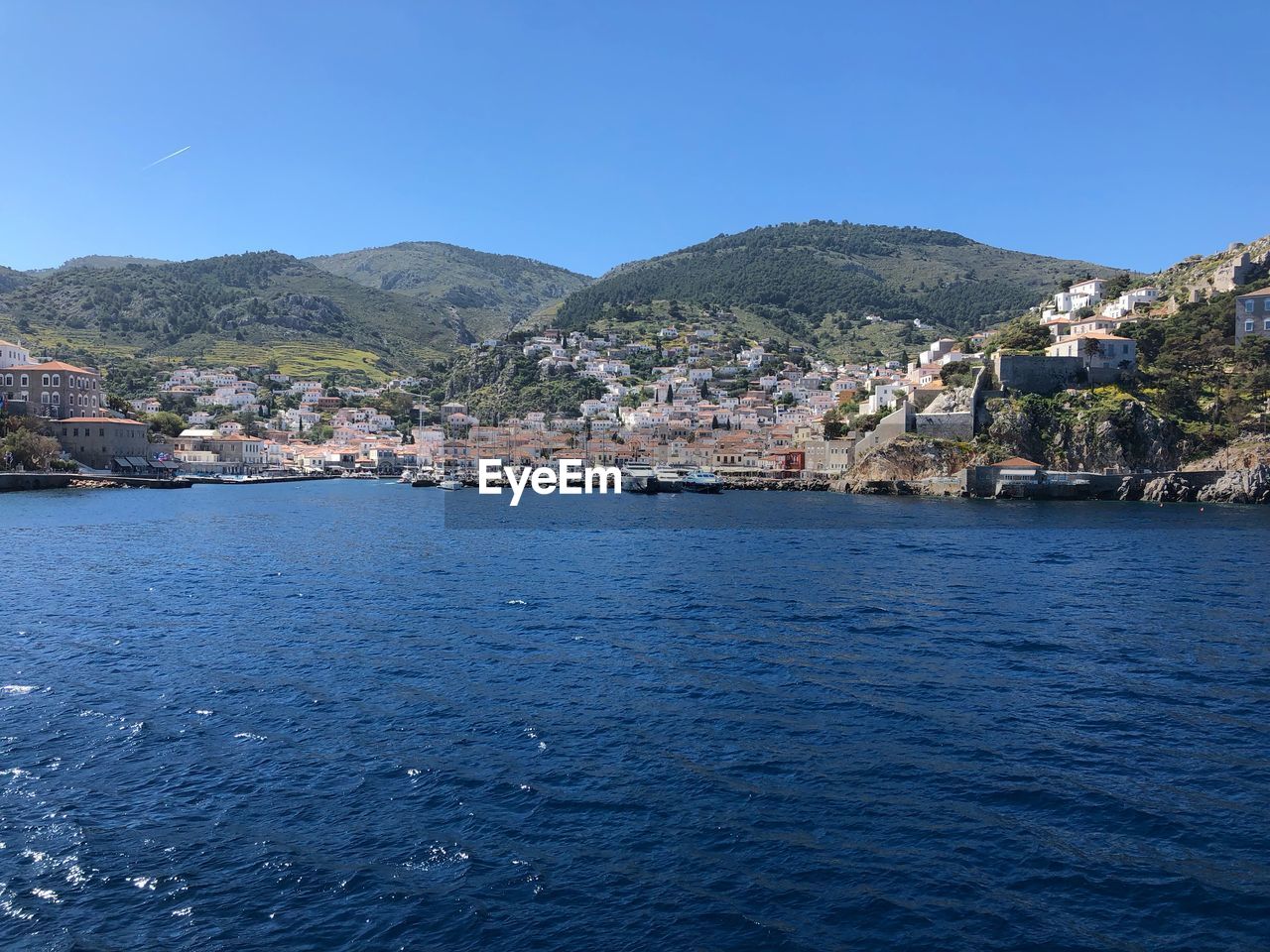 Town by sea against clear blue sky