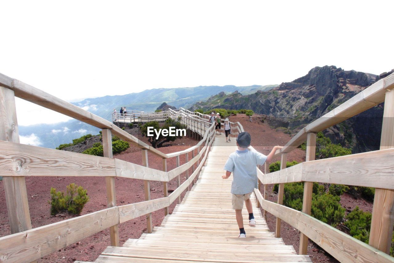 High angle view of people walking on footbridge against clear sky at pico do arieiro