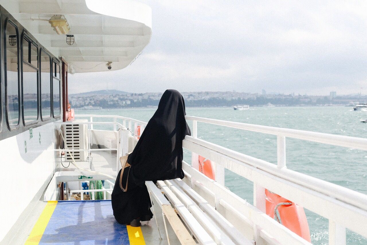 Woman in hijab at cropped boat in river